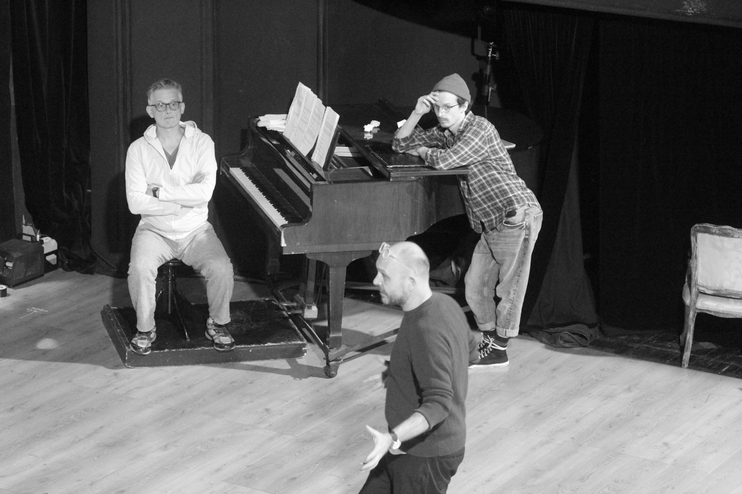 aktorzy na scenie i reżyser podczas próby teatralnej