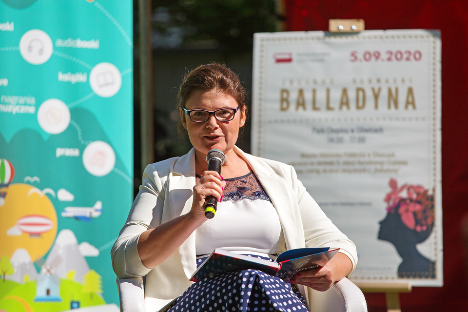 kobieta w białym żakeicie i okularach czyta książkę