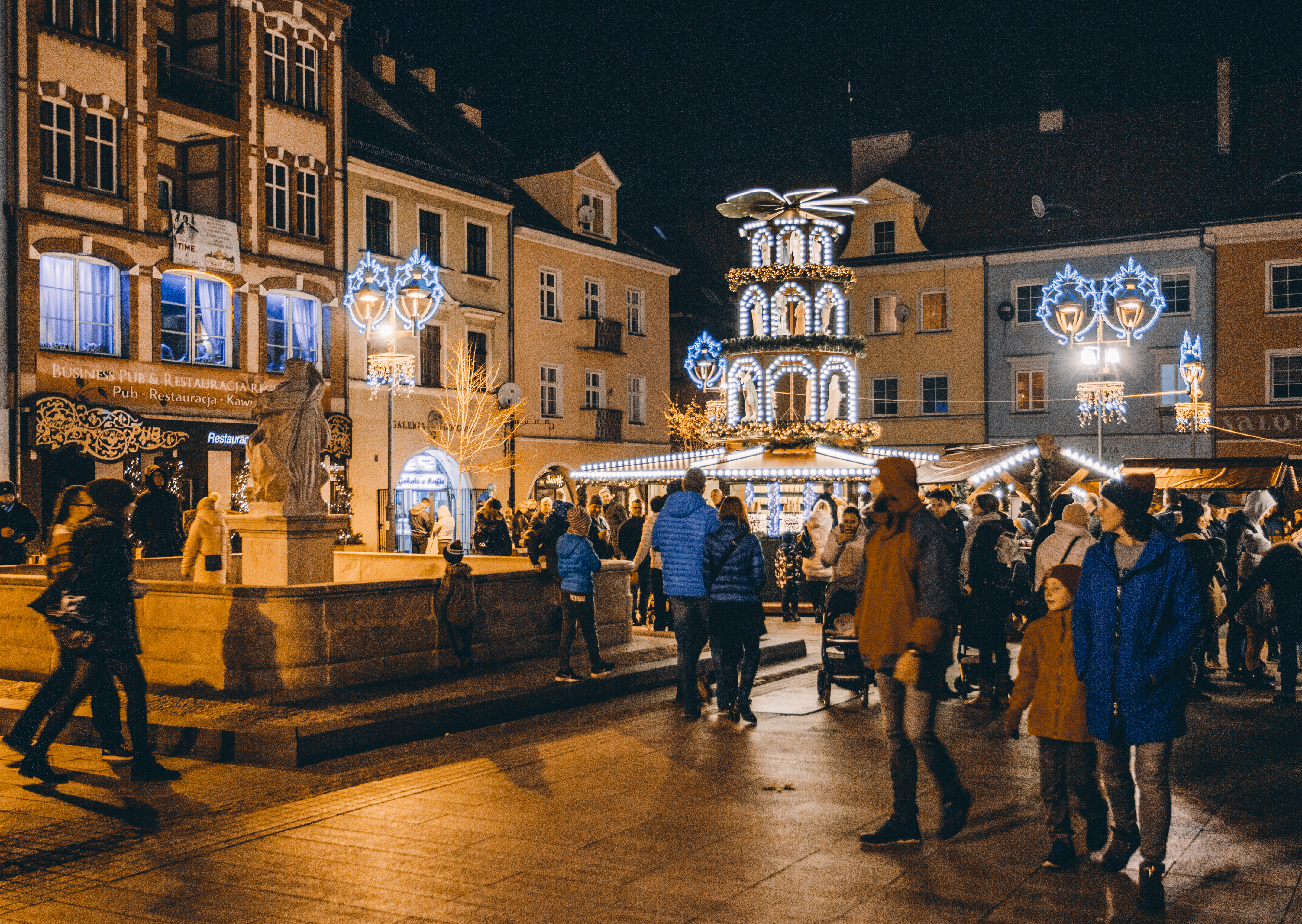 Rynek podczas jarmarku, wieczór, dużo ludzi, okolice fontanny z Neptunem