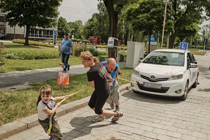 rodzina ciągnie samochód na linie