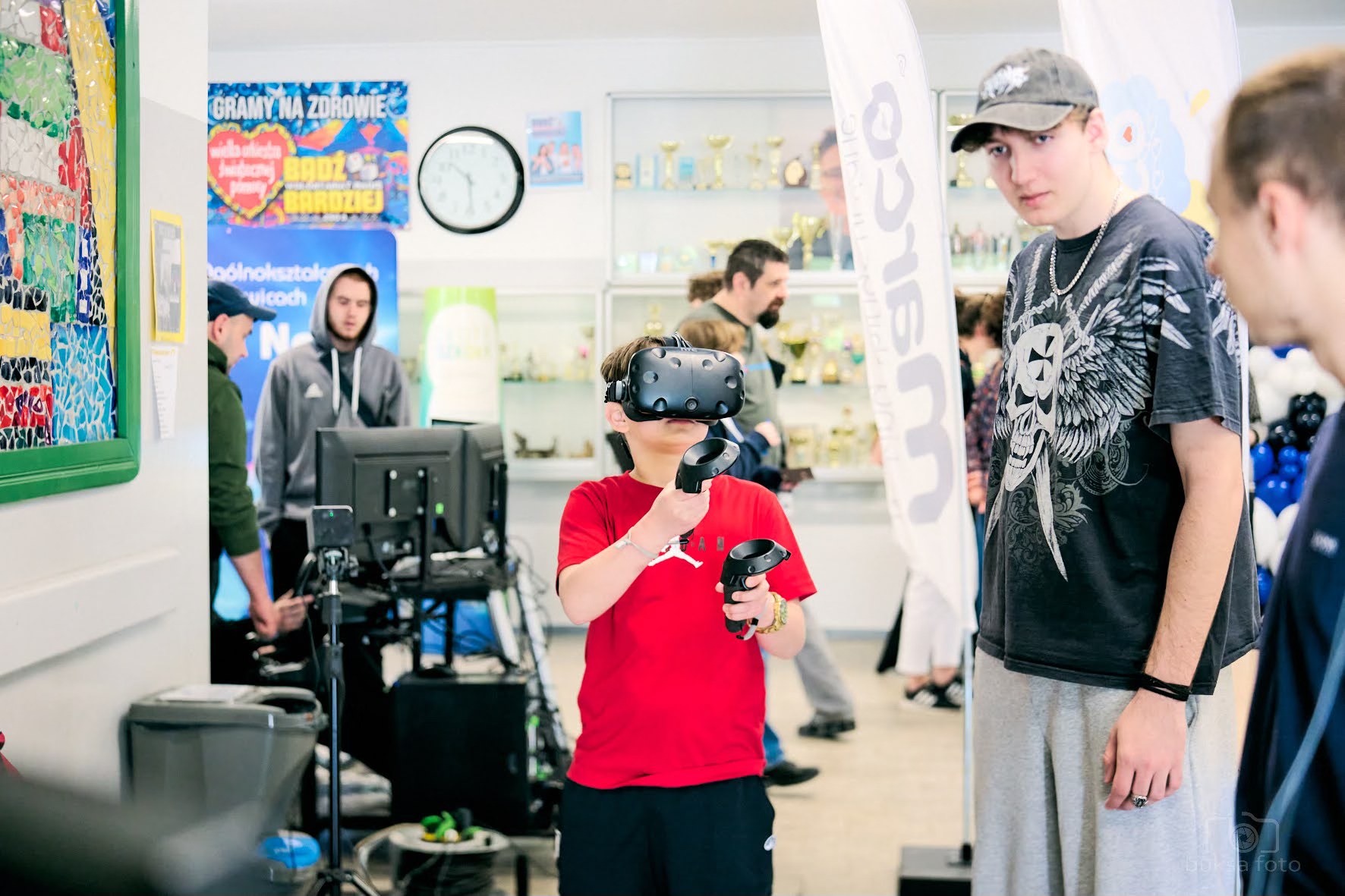 dziecko w czerwonej koszulce z goglami na twarzy, obok dwóch chłopaków