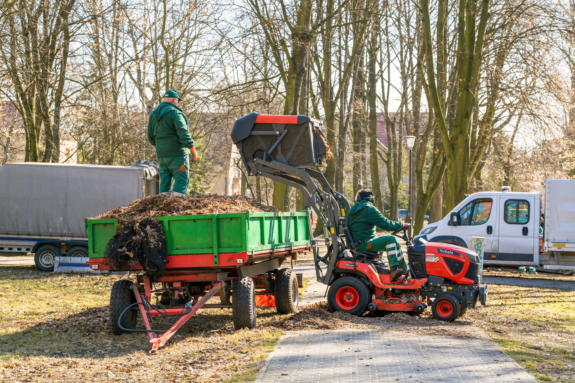 ciągnik z naczepą pełną liści i dwoje ludzi 