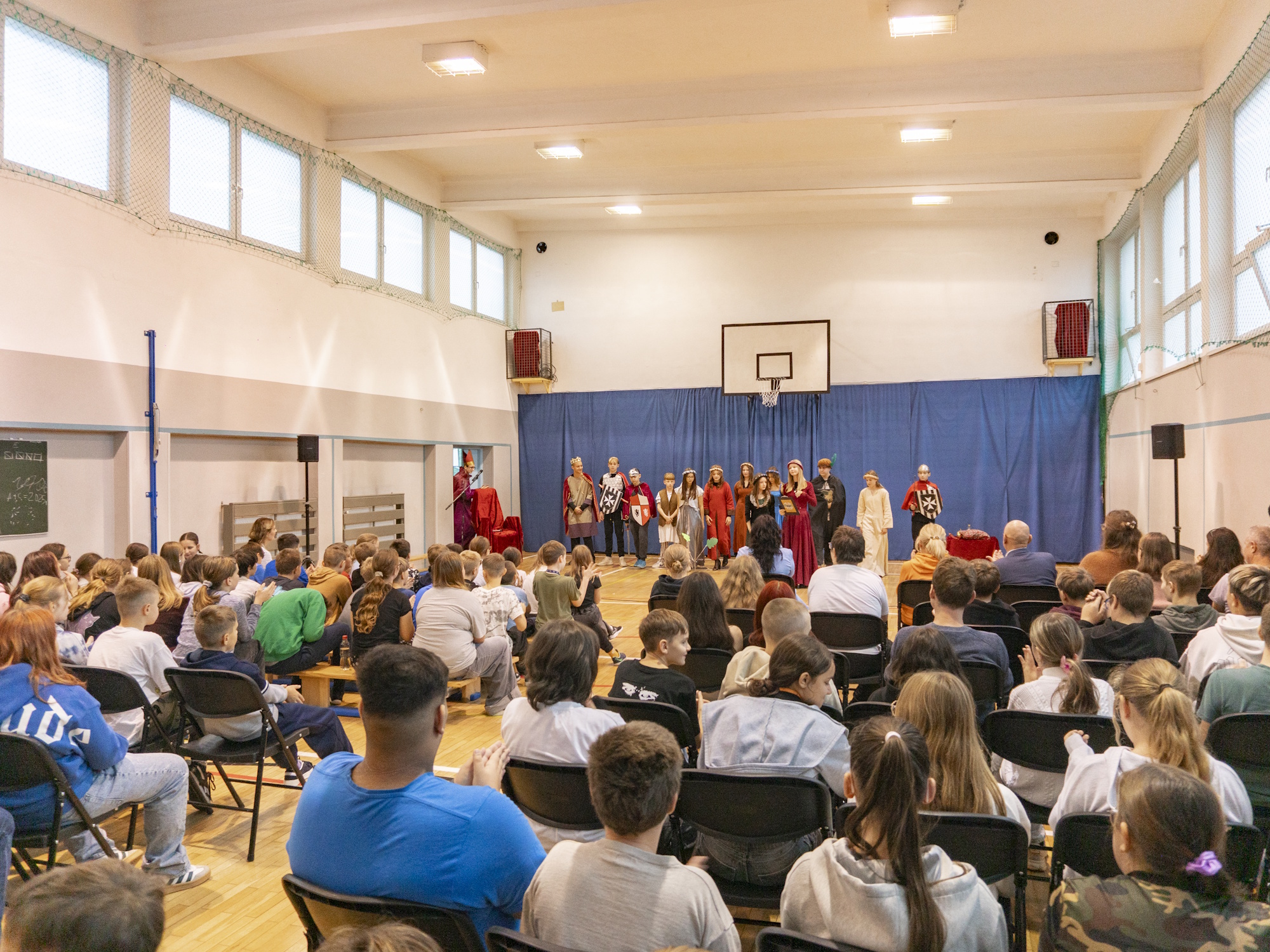 ludzie siedzący na krzesłach w sali gimnastycznej