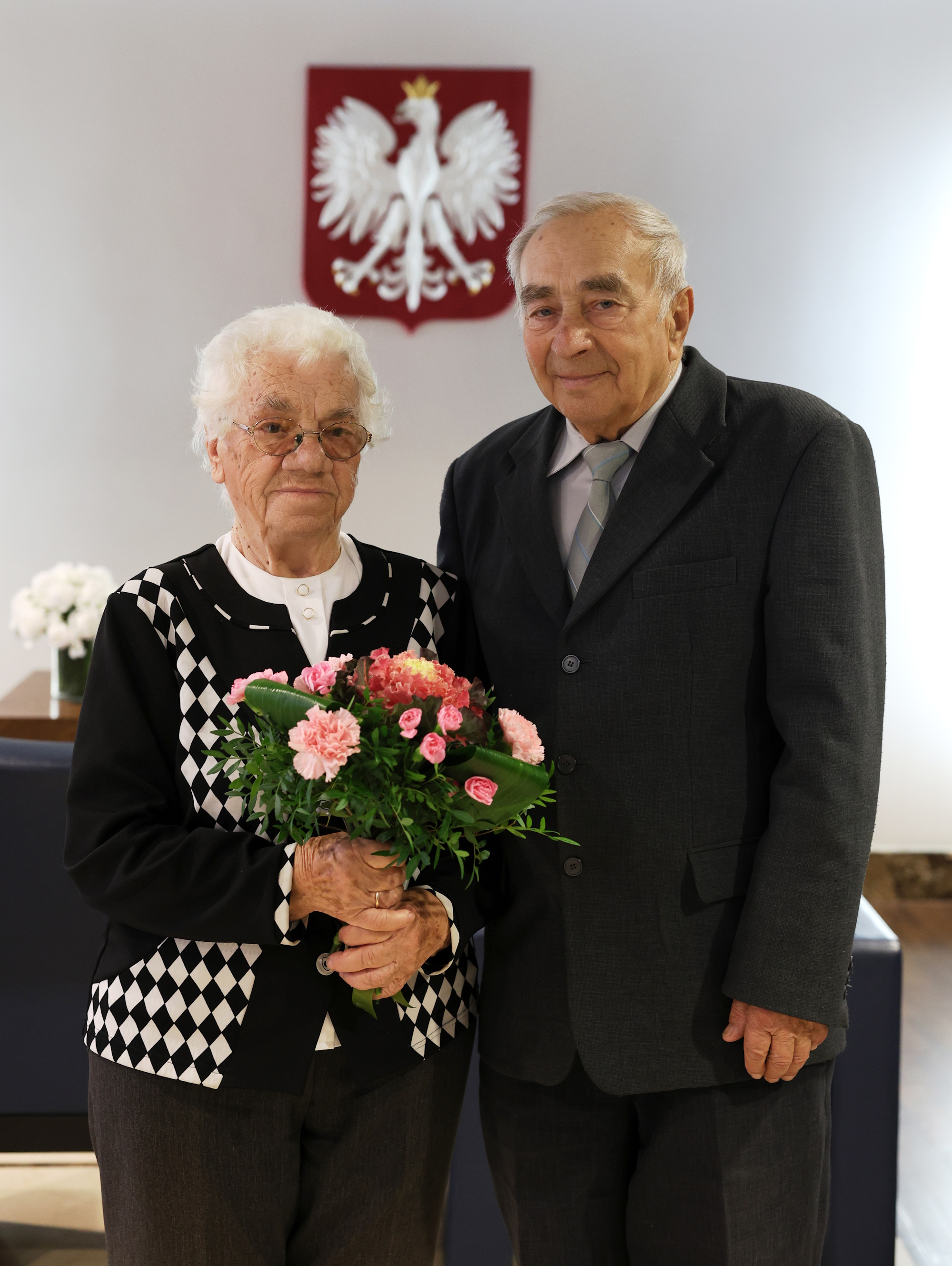 kobieta i mężczyzna patrzą w obiektyw, kobieta trzyma kwiaty