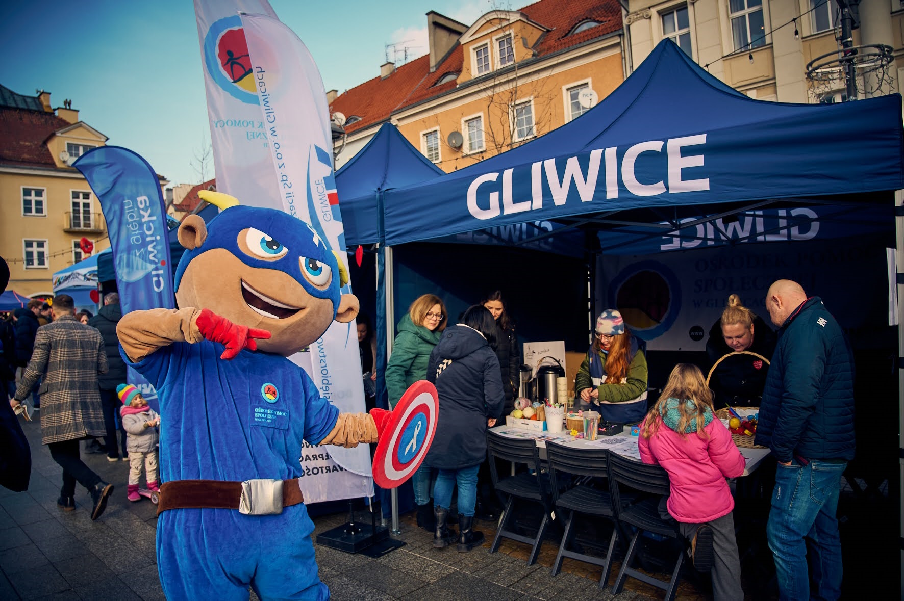 Człowiek w przebraniu Kapitana Ameryki, pokazuje na stoisko z napisem Gliwice