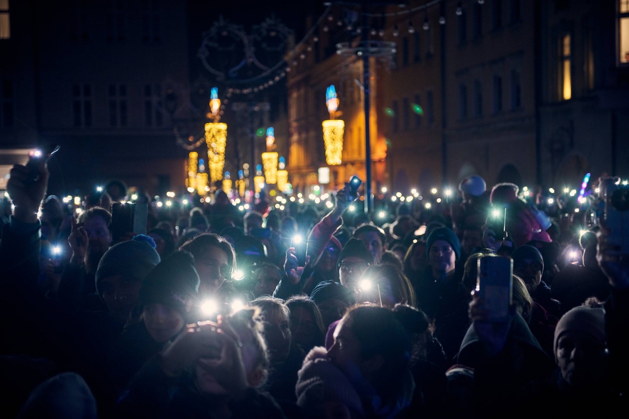 Ludzie z zapalonymi latarkami w smartfonach świecą nad siebie