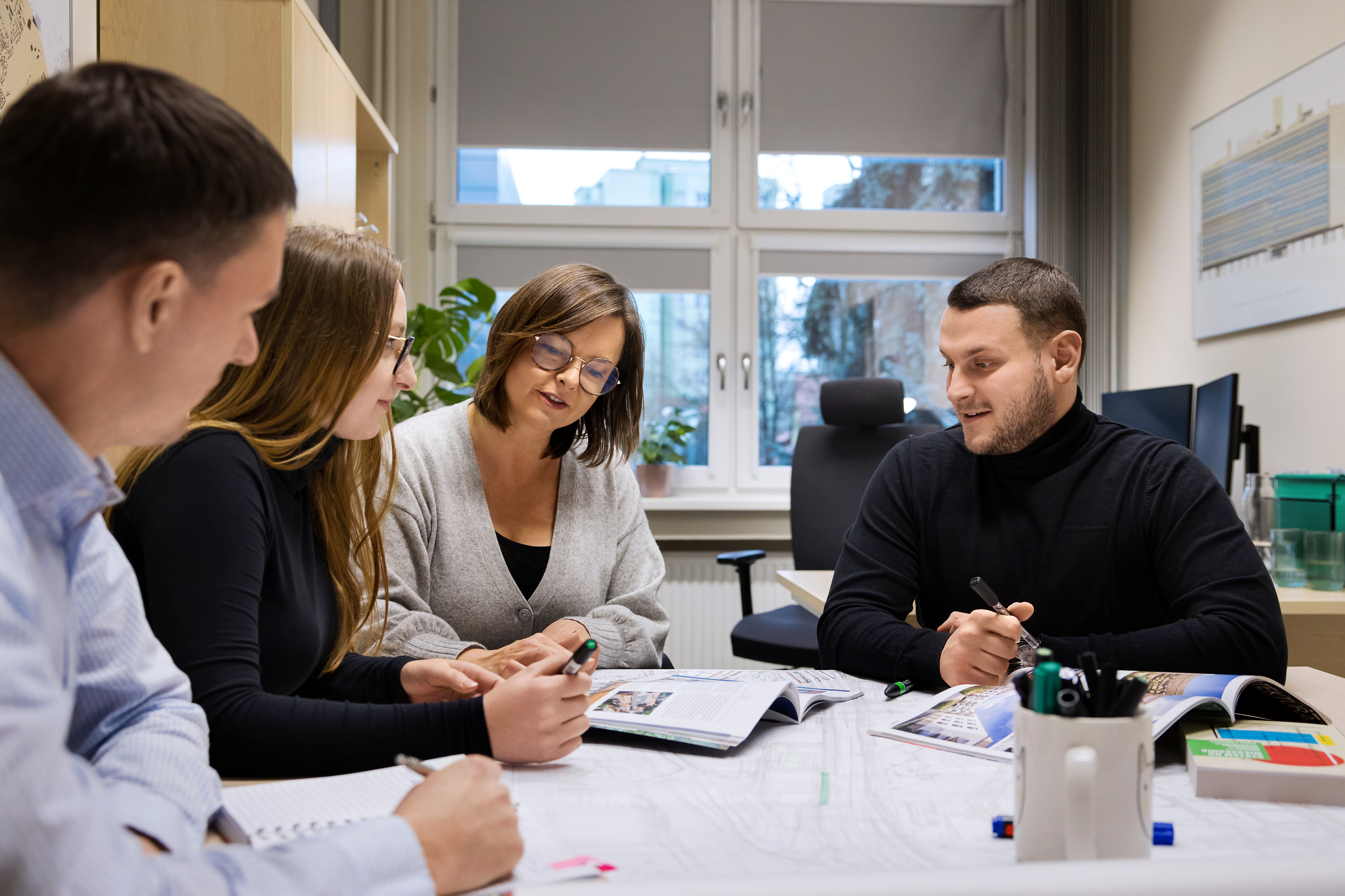 fot. D. Nita-Garbiec/UM Gliwice Czterech członków biura siedzących przy stole z projektami