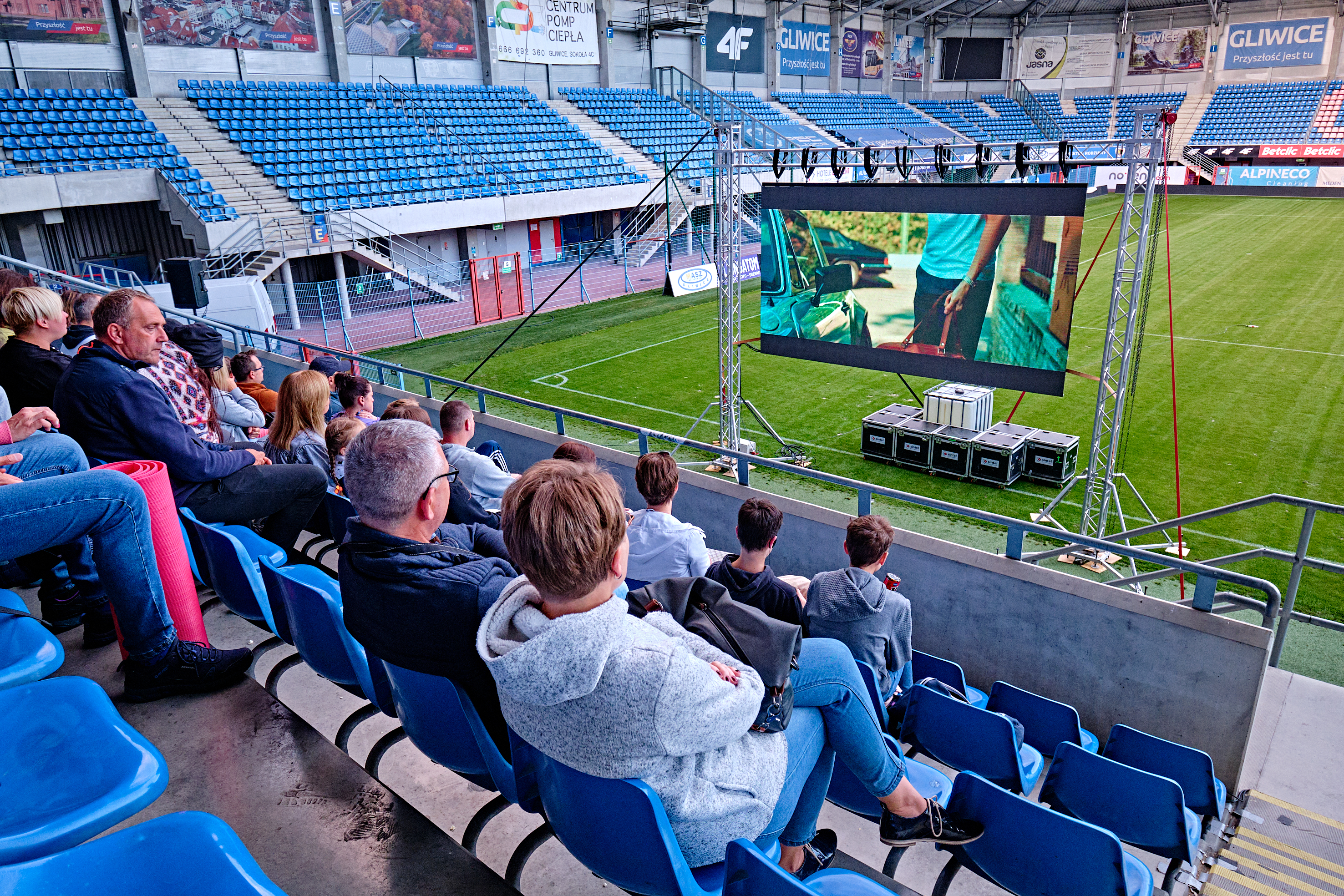 ludzie na trybunach oglądają film na telebimie