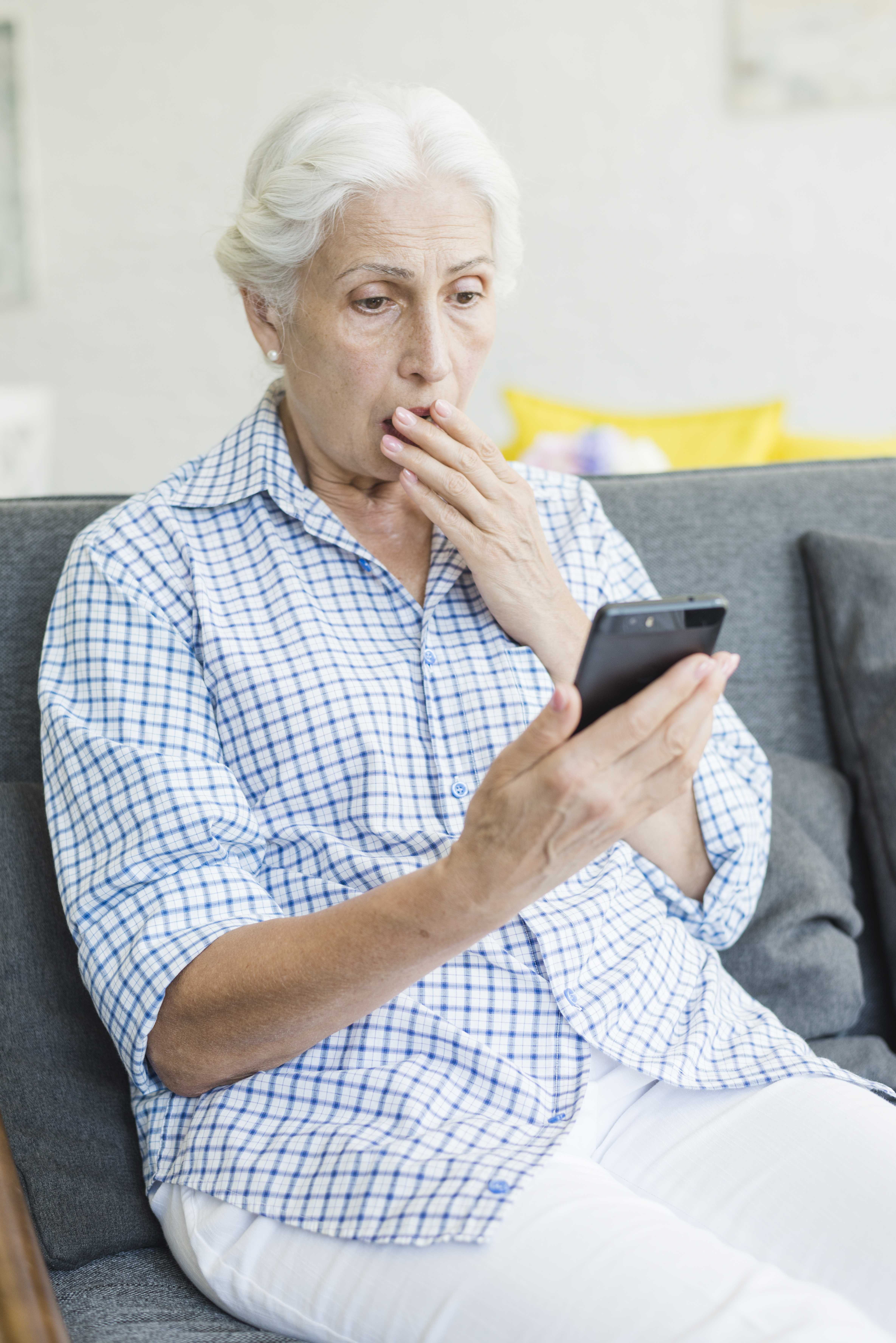 Starsza pani patrząca na telefon z przerażeniem